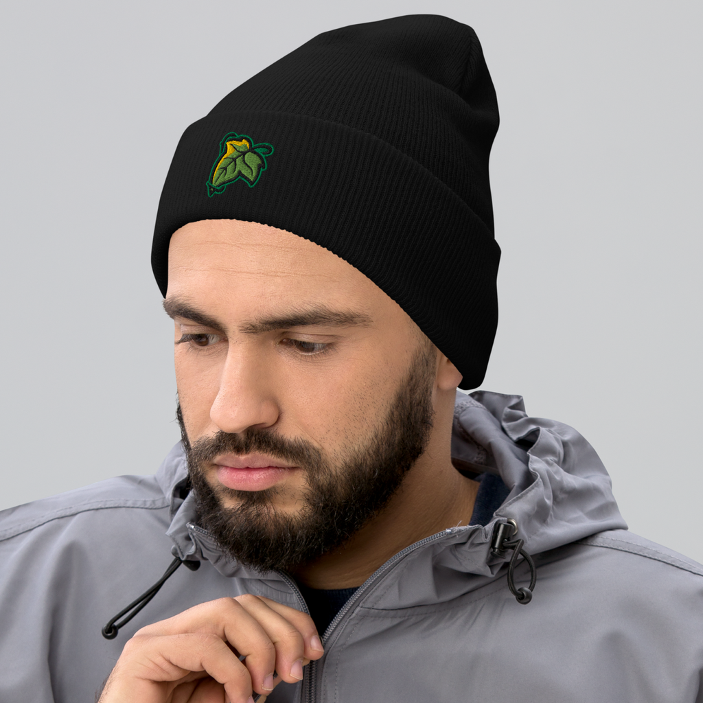 Model wearing a black Elven Brooch cuffed beanie with a green and gold leaf embroidered on the front.