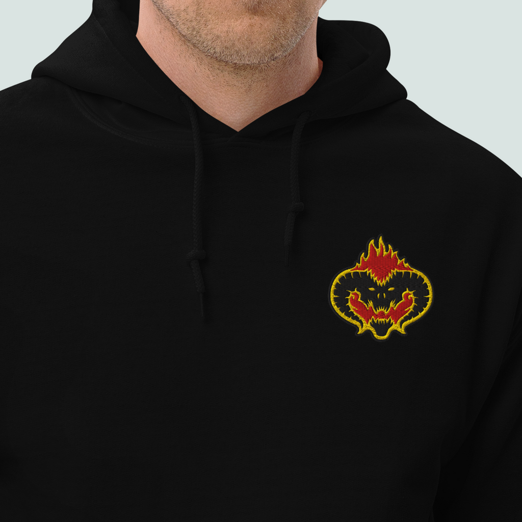 Model wearing a black Fire Demon hoodie with a horned face outlined in red and gold flames embroidered on the left chest.